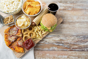 fast food and unhealthy eating concept - close up of fast food snacks and coca cola drink on wooden table