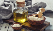 Sesame seeds and oil in a glass bottle on a wooden background